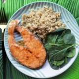 rodaja de salmón con guarnición de quinoa y hojas de espinacas