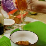 exprimiendo media naranja en cuenco con vinagreta para ensalada