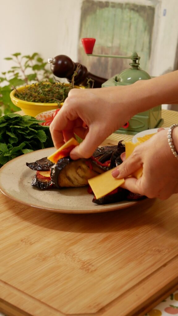 añadiendo queso en lonchas entre las ranuras de la berenjena