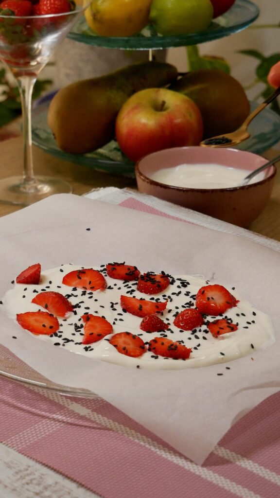 Placa de yogurt, fresas y sésamo sobre papel de horno