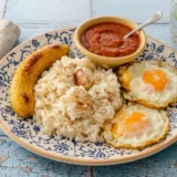 plato con arroz blanco, huevos fritos, platanos fritos y salsa de tomate